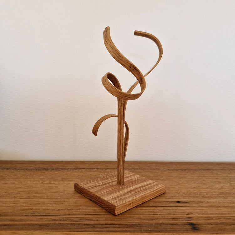 Side view of Upcycled Wood Design timber sculpture showing organic steam-bent curves and natural wood grain.