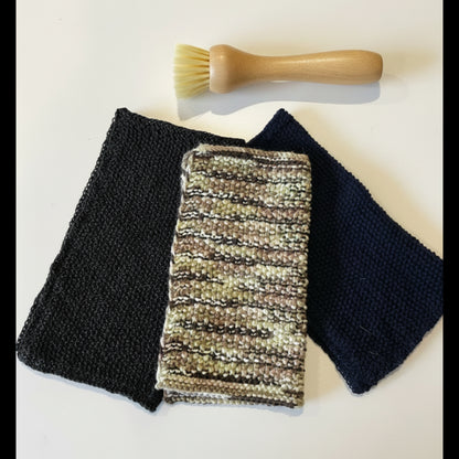 A textured upcycled acrylic dish scrubber cloth styled next to a small scrubbing brush, serving as an anti-odour, quick-drying alternative to synthetic kitchen sponges.