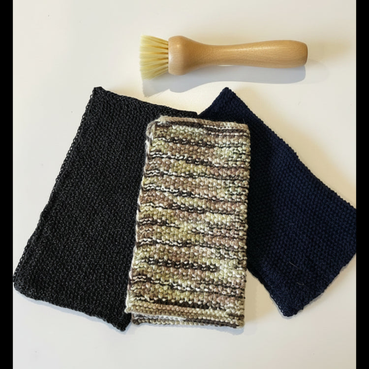 A textured upcycled acrylic dish scrubber cloth styled next to a small scrubbing brush, serving as an anti-odour, quick-drying alternative to synthetic kitchen sponges.