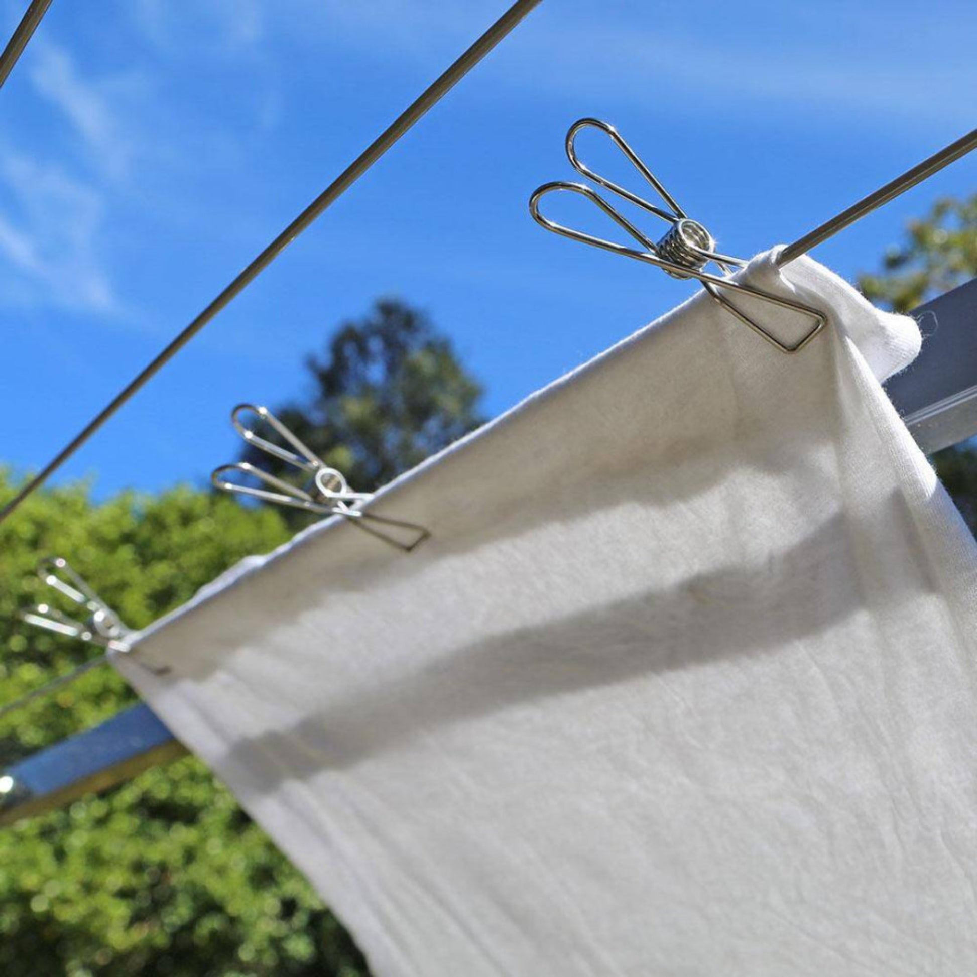 Clothesline view of a single wire-formed rust-resistant stainless steel clothes peg displaying its ergonomic loop spring mechanics on a on a towel.