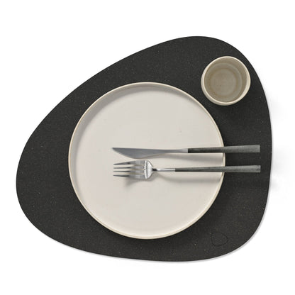 Curve recycled leather placemat featuring the signature LIND DNA Hippo texture in black anthracite with plate, fork, knife and cup.