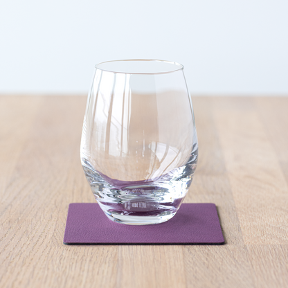 Square recycled leather coaster featuring the signature LIND DNA hippo texture on a table with a glass.
