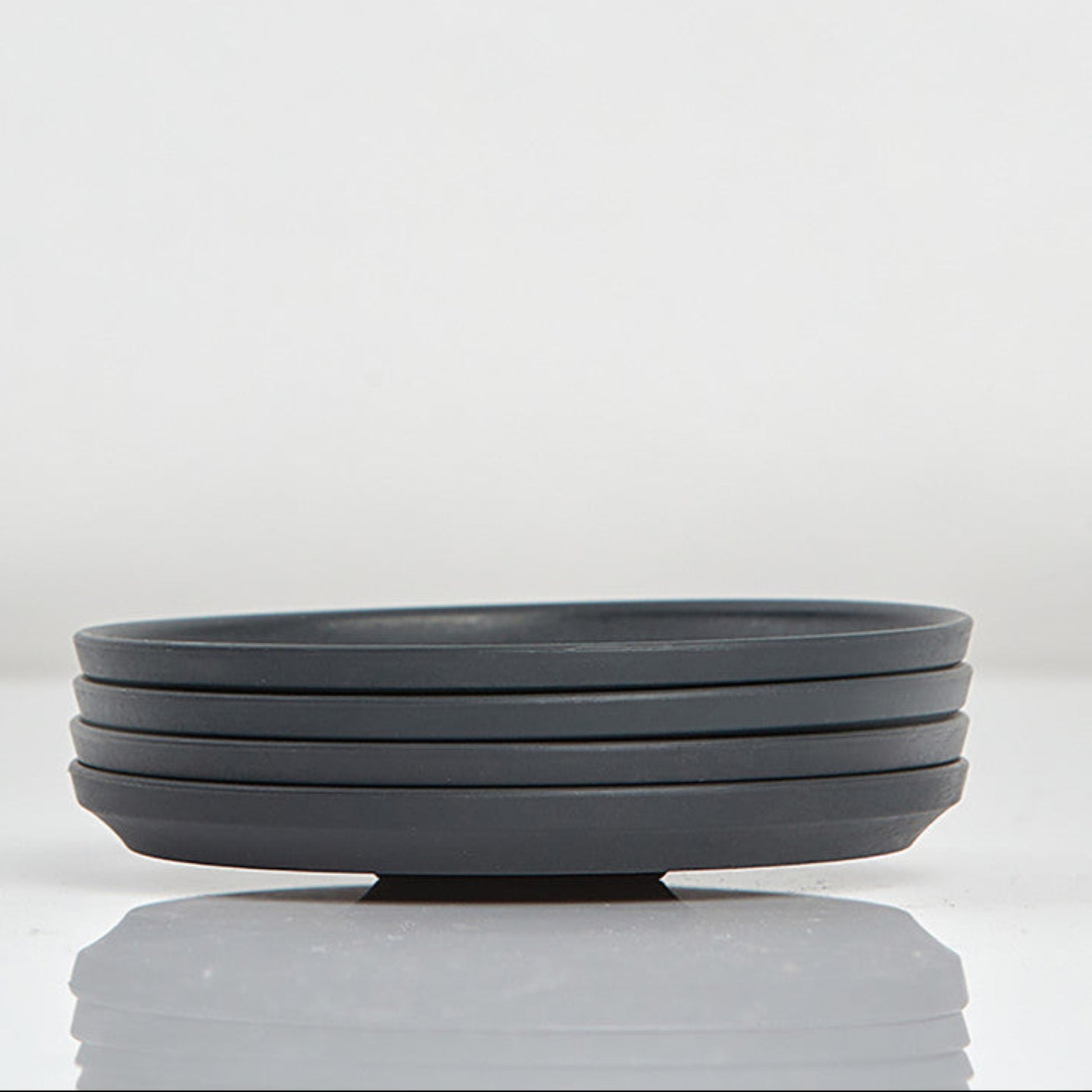 Pack of 4 Huskee small 3oz espresso saucers featuring the signature vertical ribbed design made from sustainable coffee husk waste side view In charcoal.