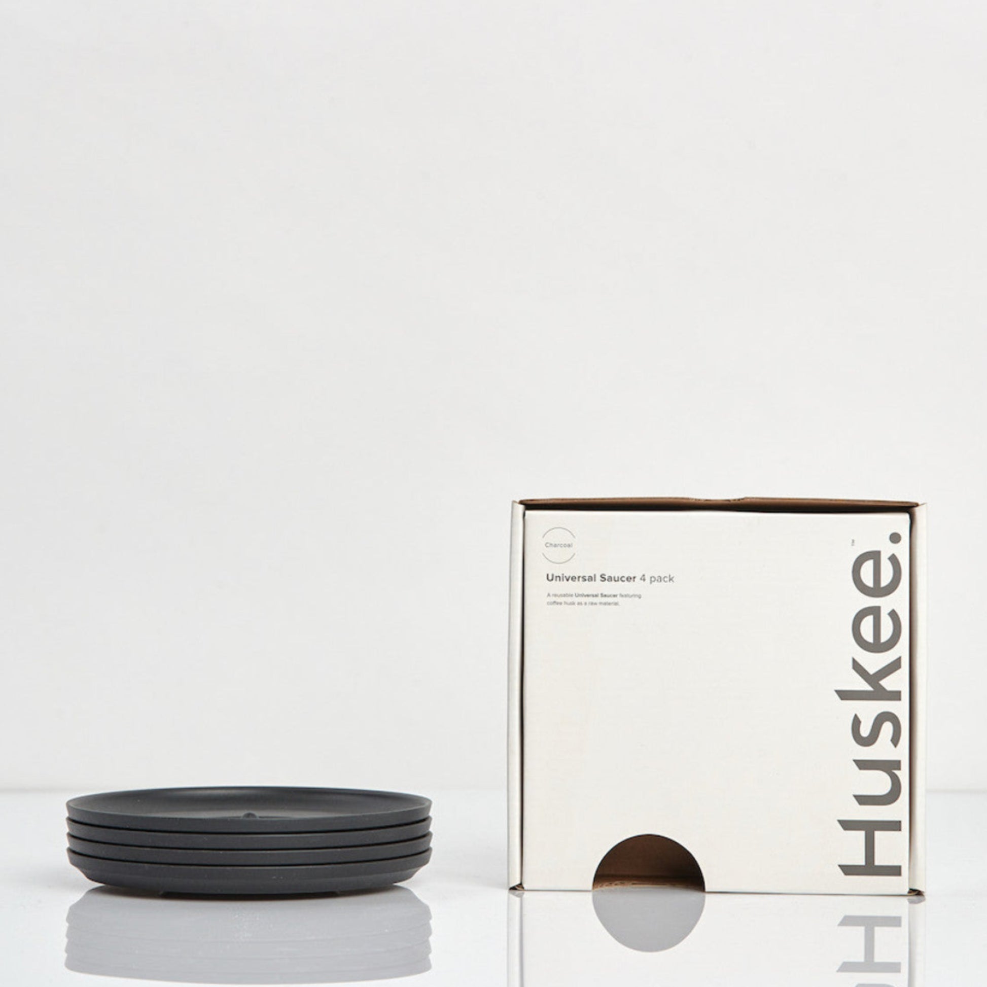 Pack of 4 universal Huskee Classic coffee saucers made from sustainable coffee husk waste with its box in charcoal.