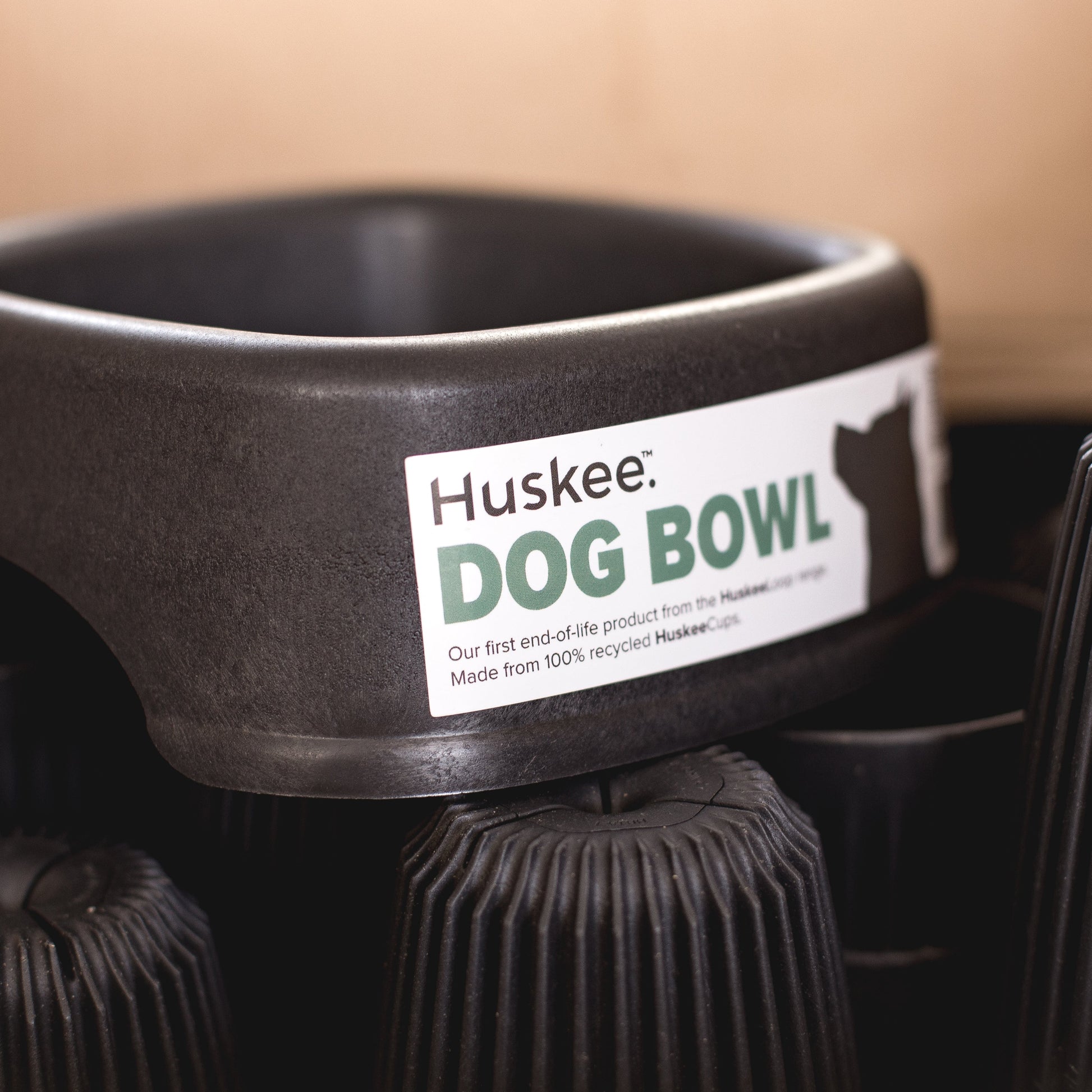 Charcoal Huskee recycled Huskee cup Dog Bowl sitting on a pile of Huskee Original recycled coffee husk cups