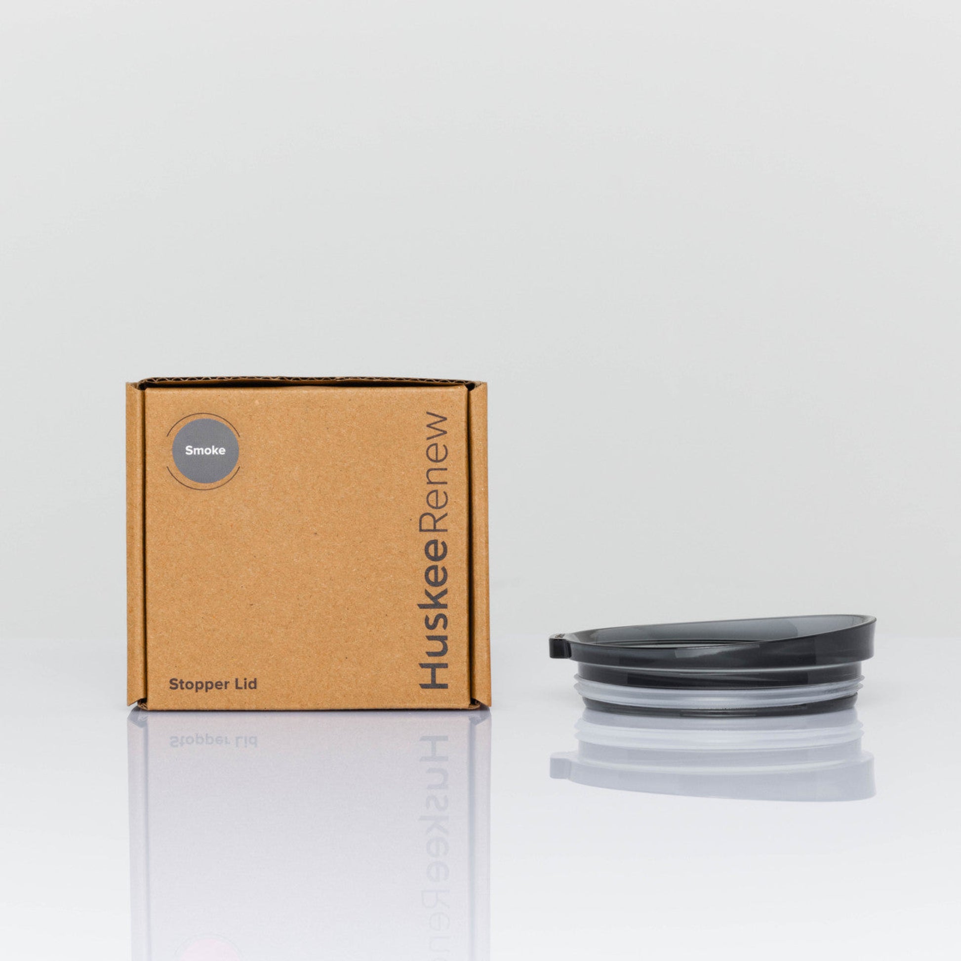 A single individual universal Huskee stopper lid featuring a spill-proof reusable design with integrated silicone seal in smoke with box.