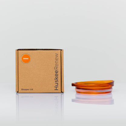 A single individual universal Huskee stopper lid featuring a spill-proof reusable design with integrated silicone seal in amber with box.
