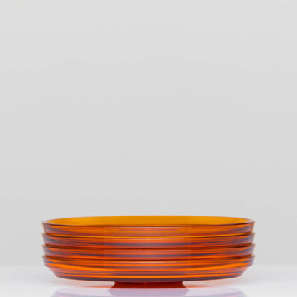 Pack of 4 HuskeeRenew translucent reusable small 3oz espresso saucers featuring the signature vertical ribbed design made from high-performance recycled polymer side view in amber.
