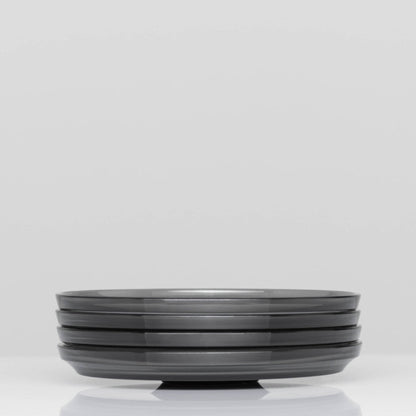 Pack of 4 HuskeeRenew translucent reusable small 3oz espresso saucers featuring the signature vertical ribbed design made from high-performance recycled polymer side view in smoke.
