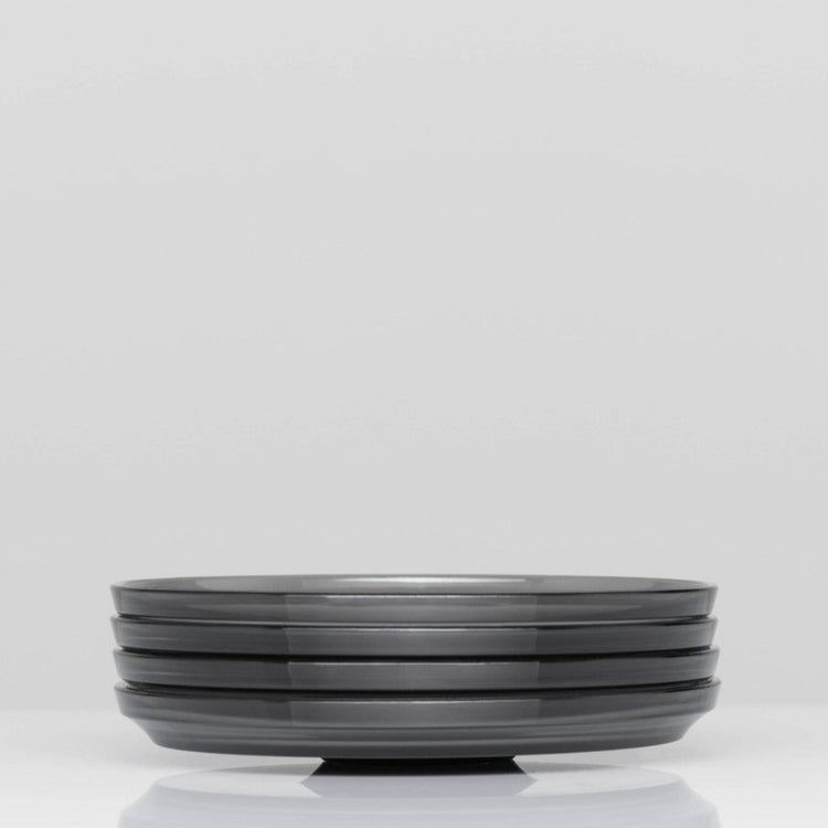 Pack of 4 HuskeeRenew translucent reusable small 3oz espresso saucers featuring the signature vertical ribbed design made from high-performance recycled polymer side view in smoke.