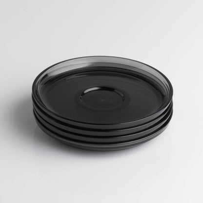 Pack of 4 HuskeeRenew translucent reusable small 3oz espresso saucers featuring the signature vertical ribbed design made from high-performance recycled polymer top view in smoke.