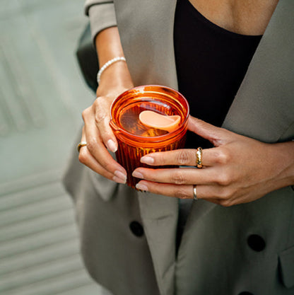  a woman carrying a HuskeeRenew cup with lid made from premium translucent recycled polymer