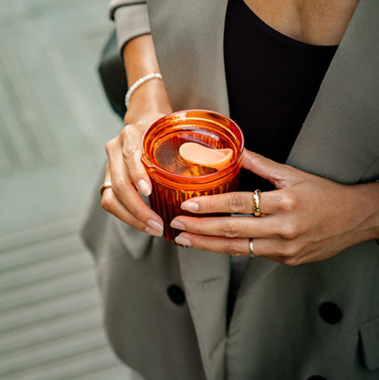  a woman carrying a HuskeeRenew cup with lid made from premium translucent recycled polymer