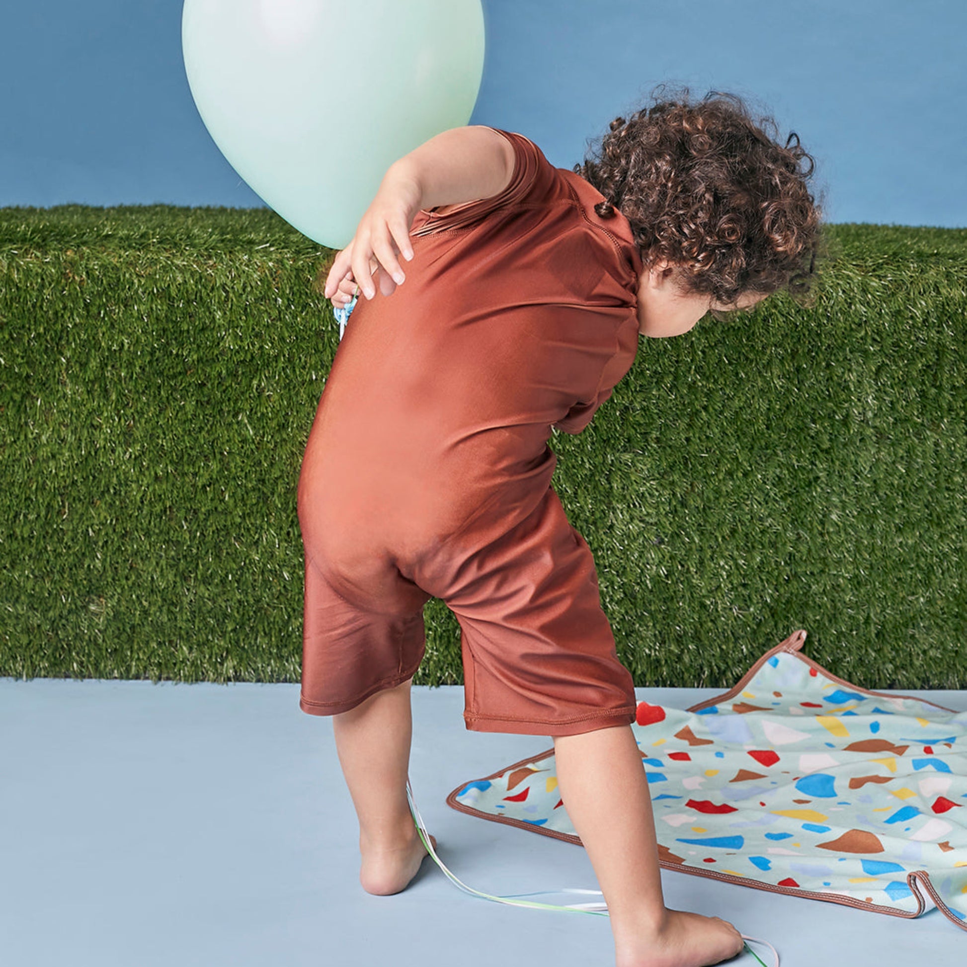 Young child playing showing the back view of Tyoub bear on the beach.