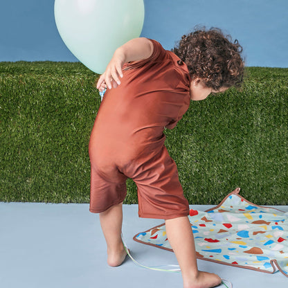 Young child playing showing the back view of Tyoub bear on the beach.