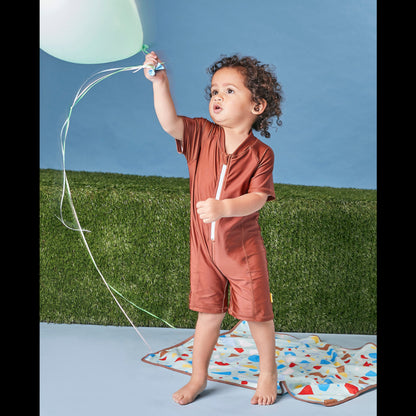 Young child playing in a studio wearing the Tyoub bear on the beach shorty sunsuit bather for UV protection.