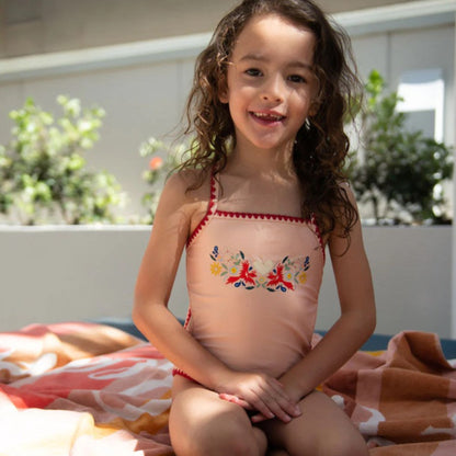 Young girl wearing the Tyoub vanilla fire bird embroidered swimsuit outdoors showing front view.