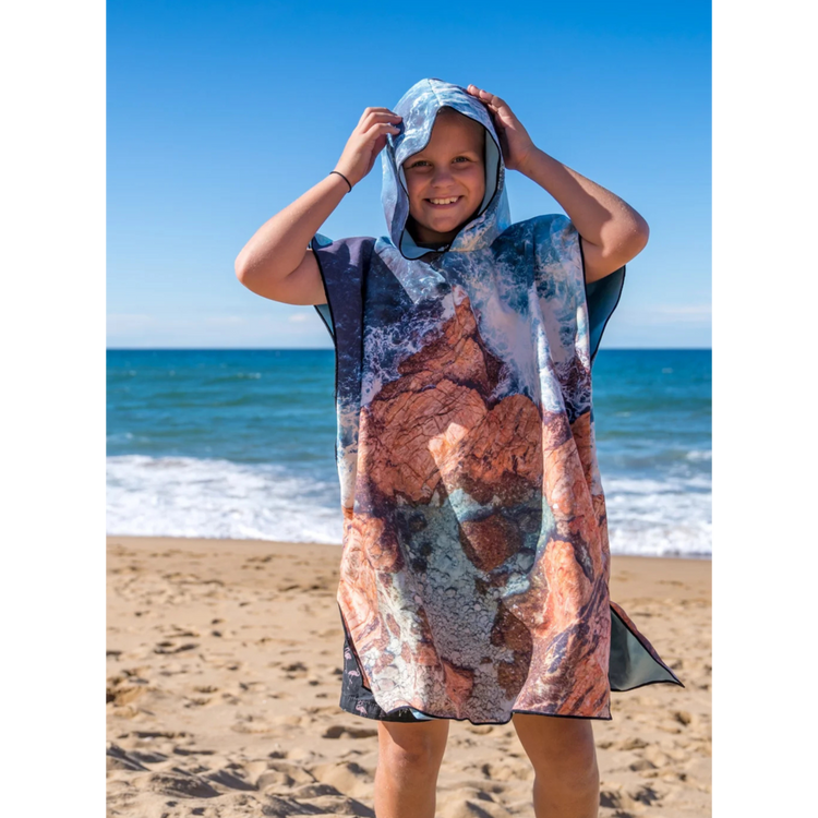 Child standing on an Australian beach wearing the Eyre print kids hooded beach towel by Will & Wind.