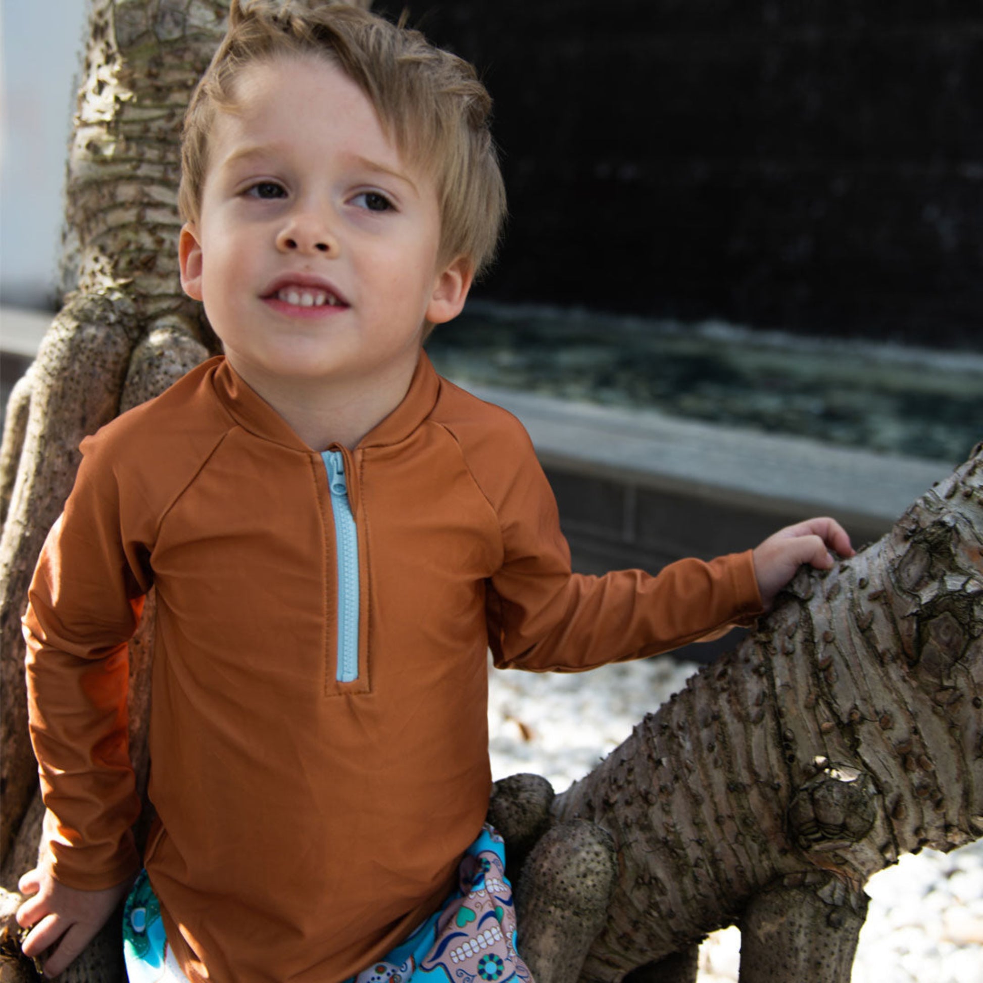 Young boy wearing the Tyoub long sleeve terracotta rash vest outdoors for sun smart UV protectionfront view.