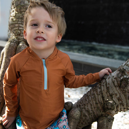 Young boy wearing the Tyoub long sleeve terracotta rash vest outdoors for sun smart UV protectionfront view.