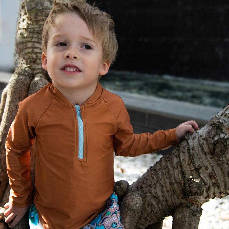 Young boy wearing the Tyoub long sleeve terracotta rash vest outdoors for sun smart UV protectionfront view.