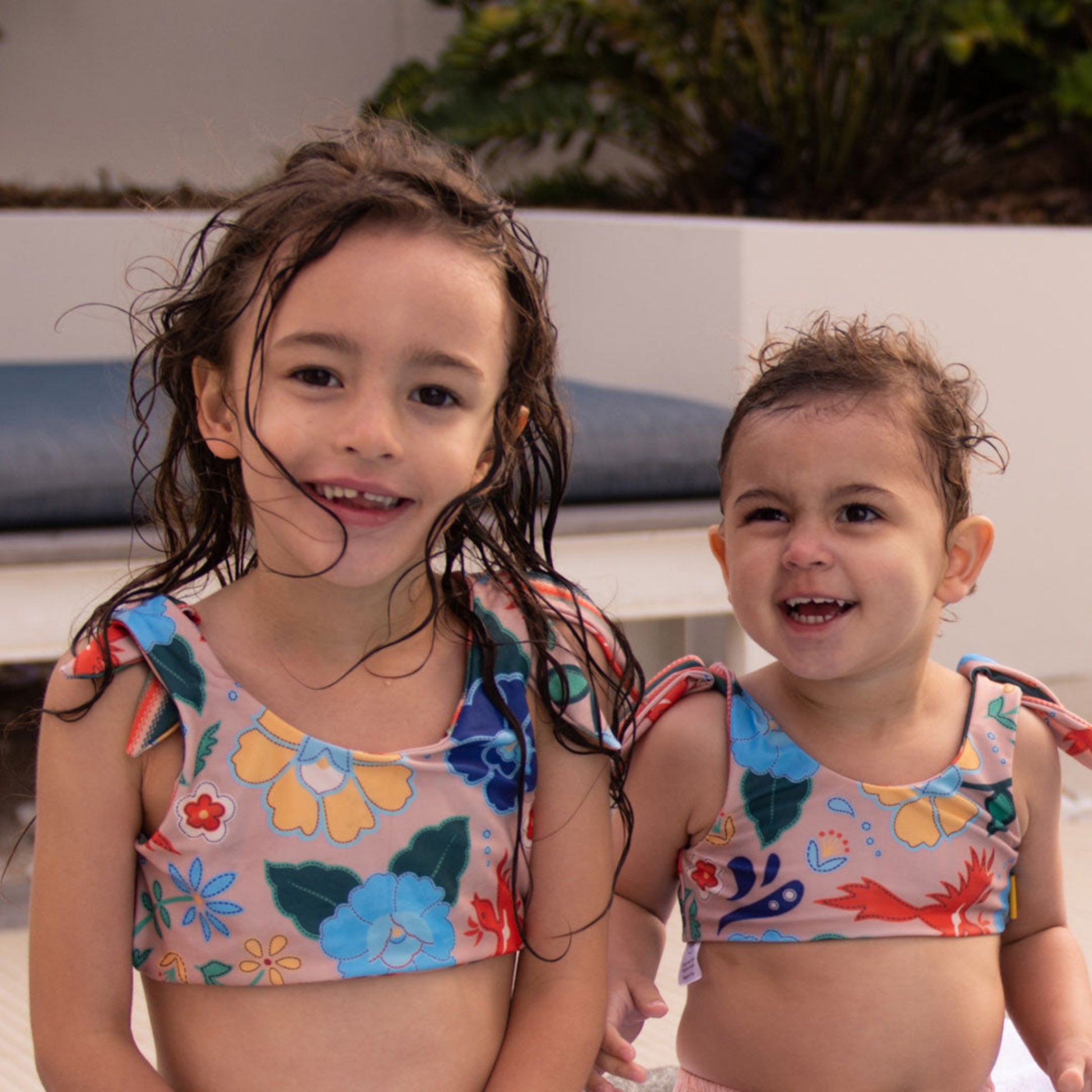 Two young girls wearing the Tyoub phoenix print reversible two piece bikini poolside in Australia.