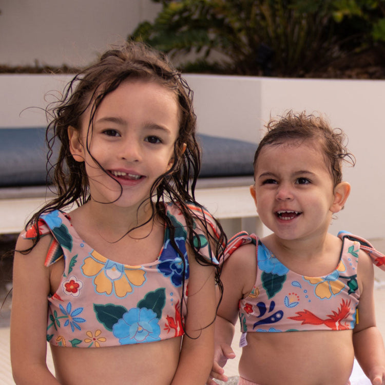 Two young girls wearing the Tyoub phoenix print reversible two piece bikini poolside in Australia.