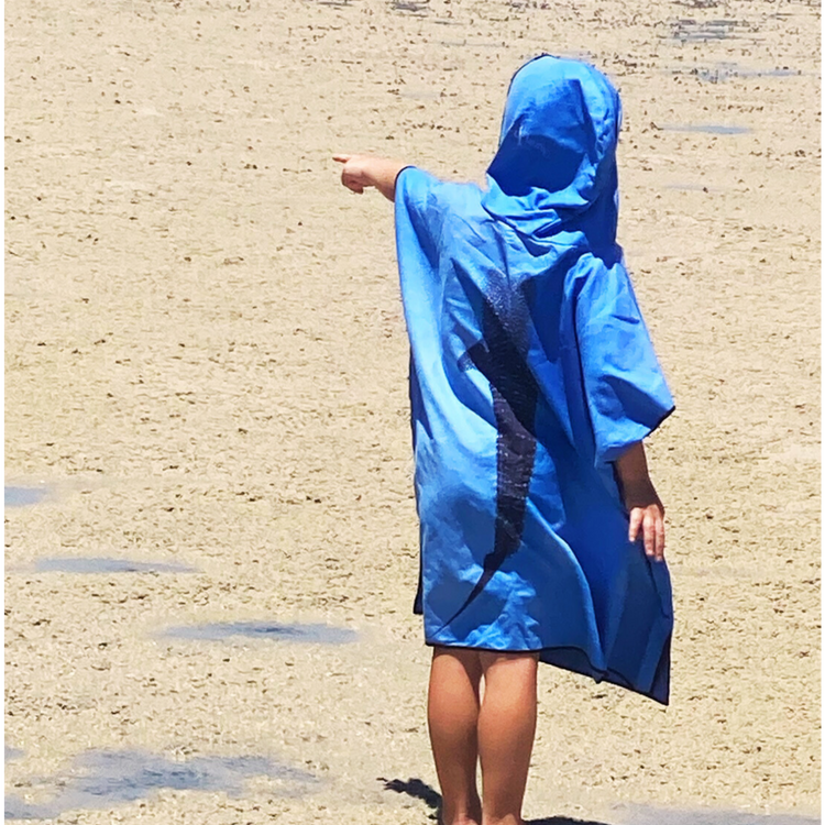 Child looking at the ocean wearing a Whale Shark print kids swimming poncho towel.