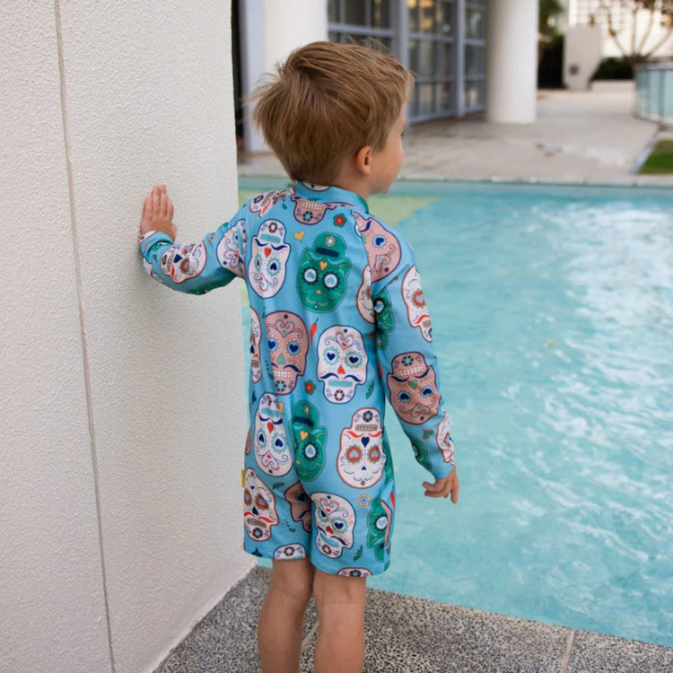 Rear view of a child wearing the aqua blue sugar skull sunsuit highlighting the full upper back and shoulder UV sun safety coverage.