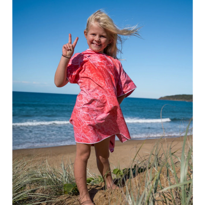 Child on a sand dune wearing a Pink Lake design kids wearable poncho beach towel.