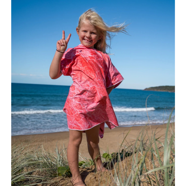 Child on a sand dune wearing a Pink Lake design kids wearable poncho beach towel.