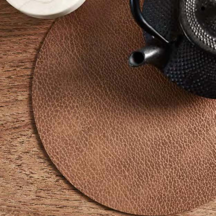 Set of 4 round LIND DNA hot mats made from 3mm thick heat-resistant recycled leather protecting a table surface from hot cookware.