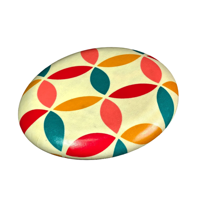 Standalone 230mm flying disc made from recycled Fijian beach waste showing vibrant, one-of-a-kind upcycled colour patterns in geometric.