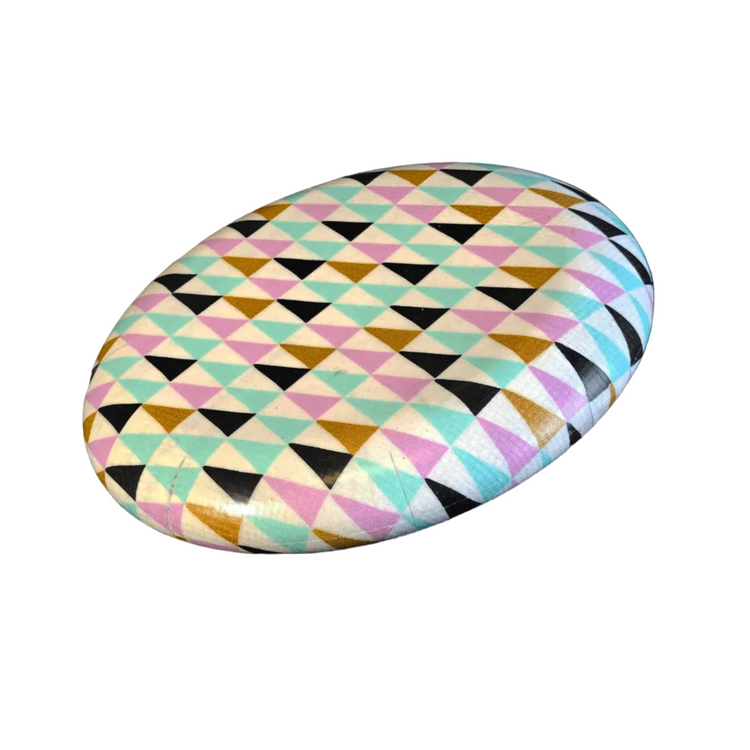 Standalone 230mm flying disc made from recycled Fijian beach waste showing vibrant, one-of-a-kind upcycled colour patterns in triangles.