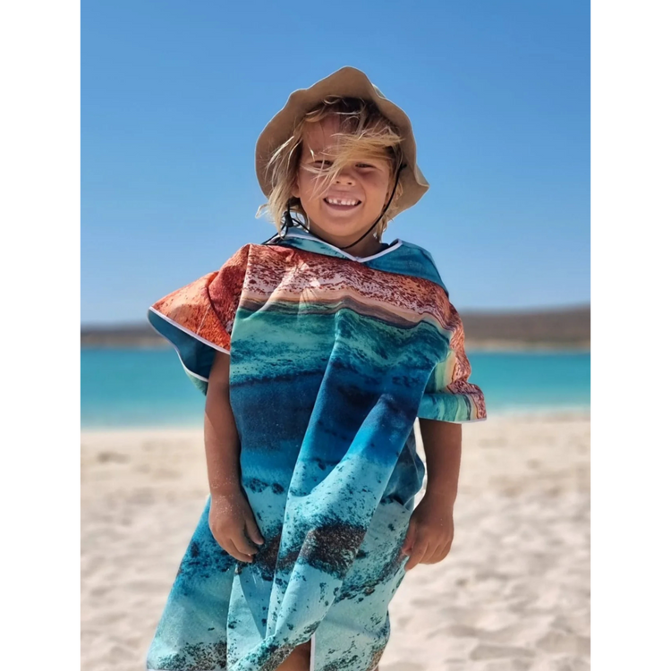 Child at the beach wearing the Ningaloo aerial print microfibre toddler hooded swim towel.