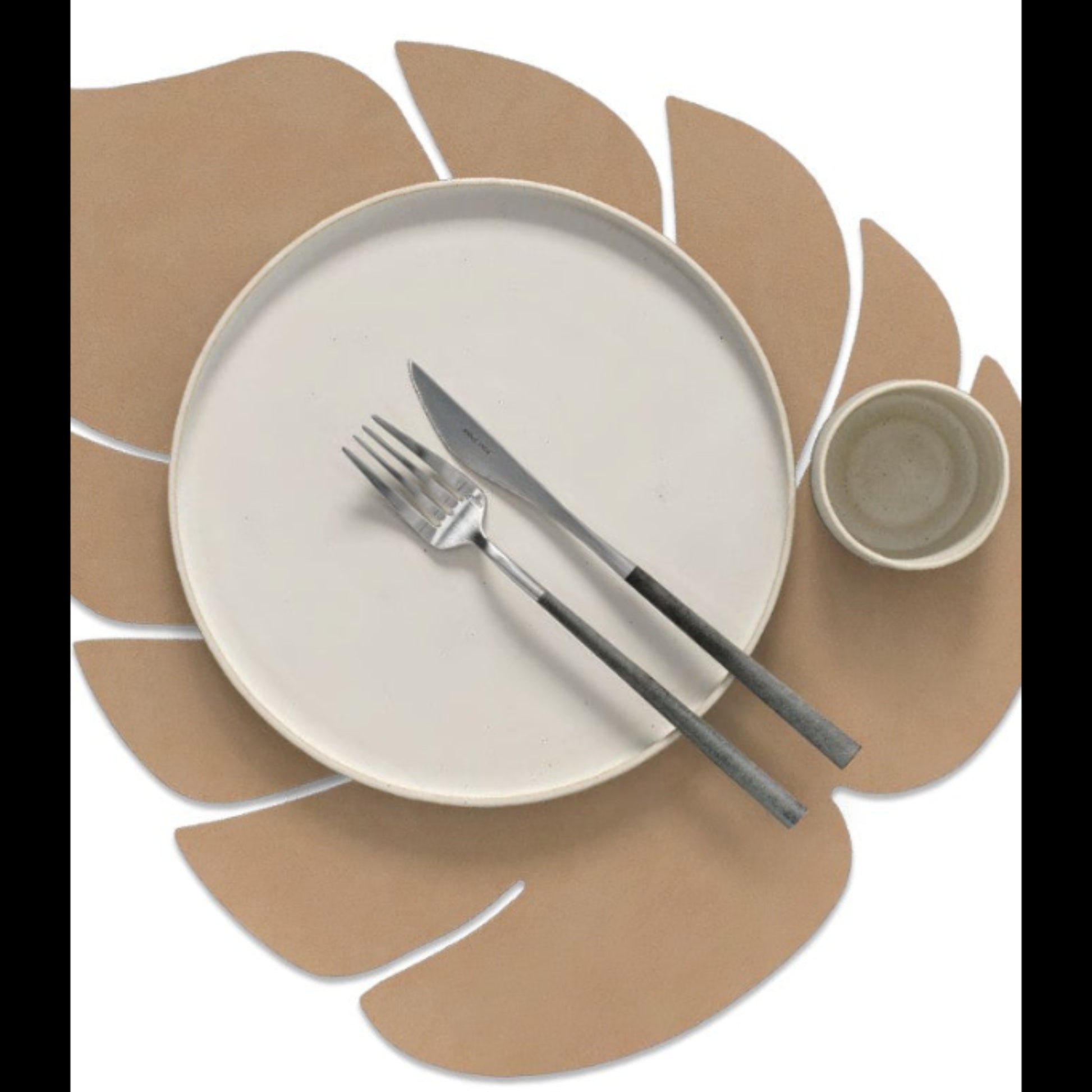 Monstera leaf recycled leather placemat styled with a plate, cup, kinfe and fork.