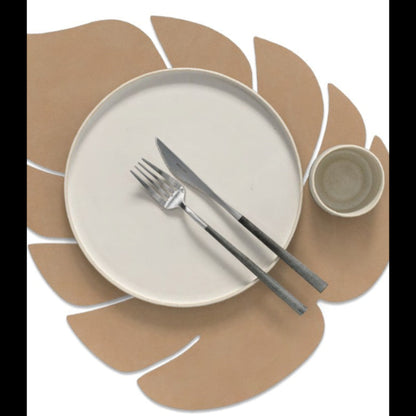Monstera leaf recycled leather placemat styled with a plate, cup, kinfe and fork.