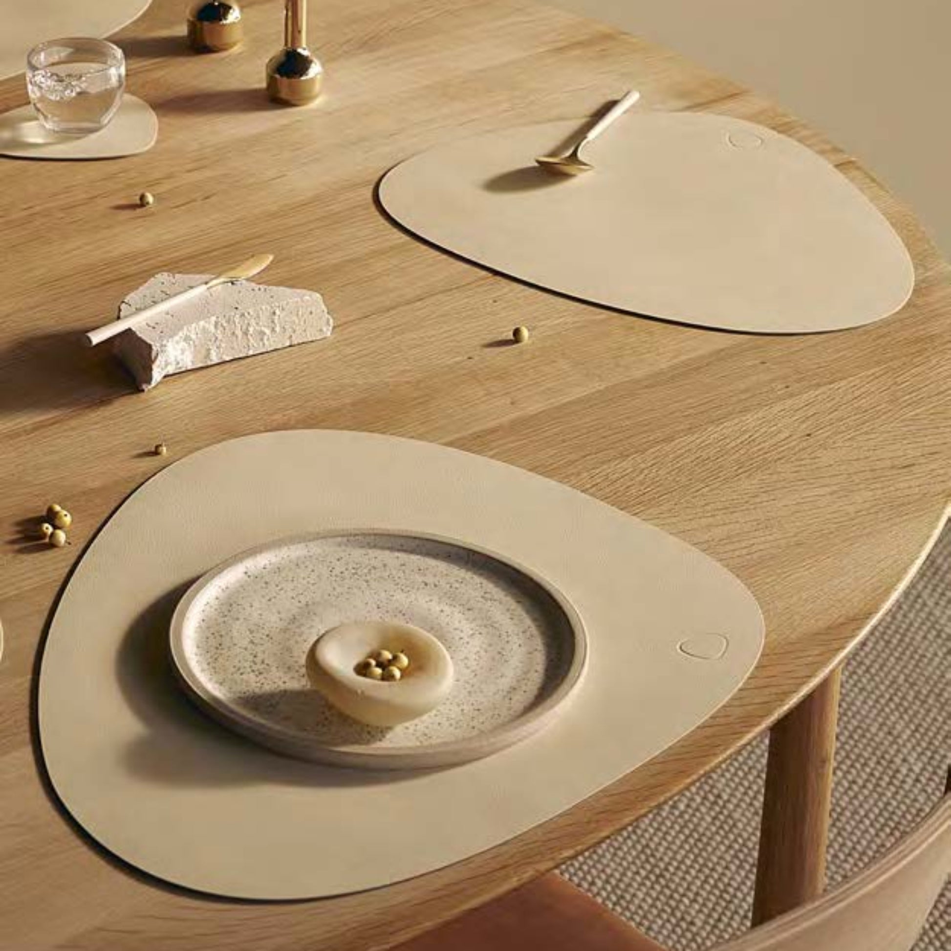 Curve recycled leather placemat featuring the signature LIND DNA Nupo texture on a table set with plate, cheese, a small cake and glass of water.