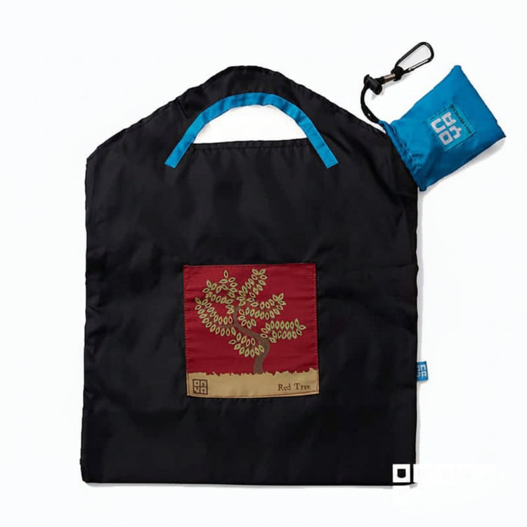 Onya reusable shopping bag with built in shoulder strap and checkout caddy loops next to its attached compact pouch on a clean white background, available in Australia in black red tree small variant.