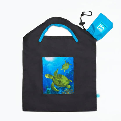 Onya reusable shopping bag with built in shoulder strap and checkout caddy loops next to its attached compact pouch on a clean white background, available in Australia in black sea turtle small variant.