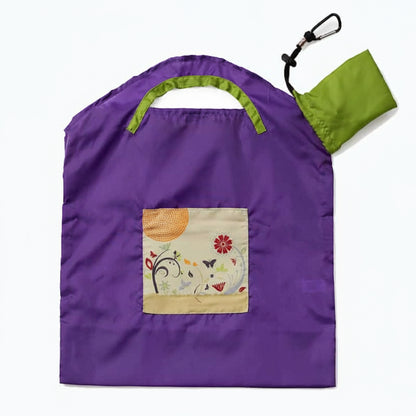 Onya reusable shopping bag with built in shoulder strap and checkout caddy loops next to its attached compact pouch on a clean white background, available in Australia in purple garden small variant.
