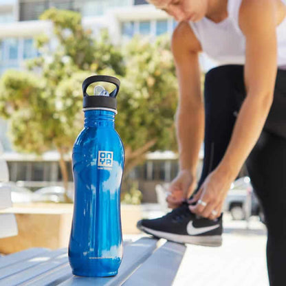 Single Onya stainless steel drink bottle 1000ml blue variant on a bench with a jogger in a park.