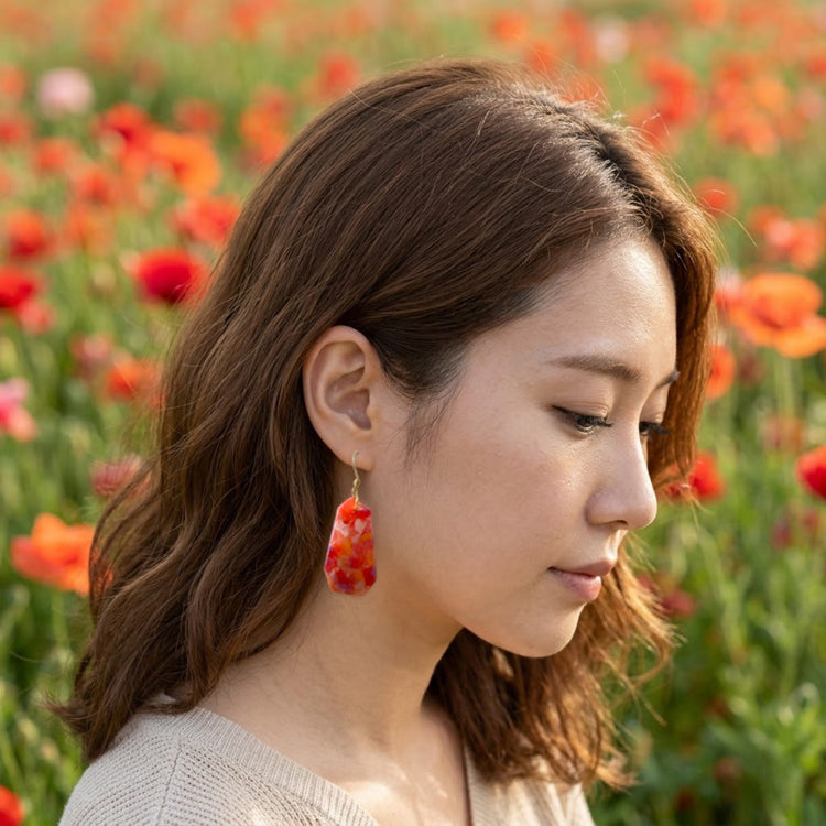 On-model style shot showing the drop length and scale of the orange red floral full bloom eco statement earrings.