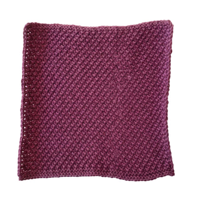 Plum handmade knitted dishcloth made from absorbent recycled cotton for kitchen and bathroom use on a white background.