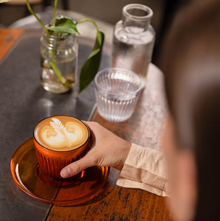 A sleek HuskeeRenew recycled classic saucer styled beneath a matching coffee cup on a modern cafe table.