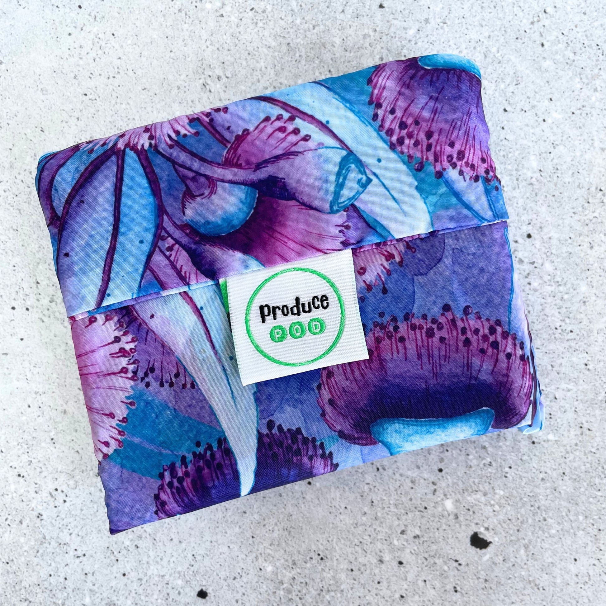 Close up view of the lightweight sixty gram reusable grocery bag folded entirely inside its own integrated self storing travel pouch for compact pocket storage. Gum blossomvariant.