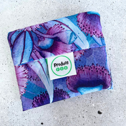 Close up view of the lightweight sixty gram reusable grocery bag folded entirely inside its own integrated self storing travel pouch for compact pocket storage. Gum blossomvariant.
