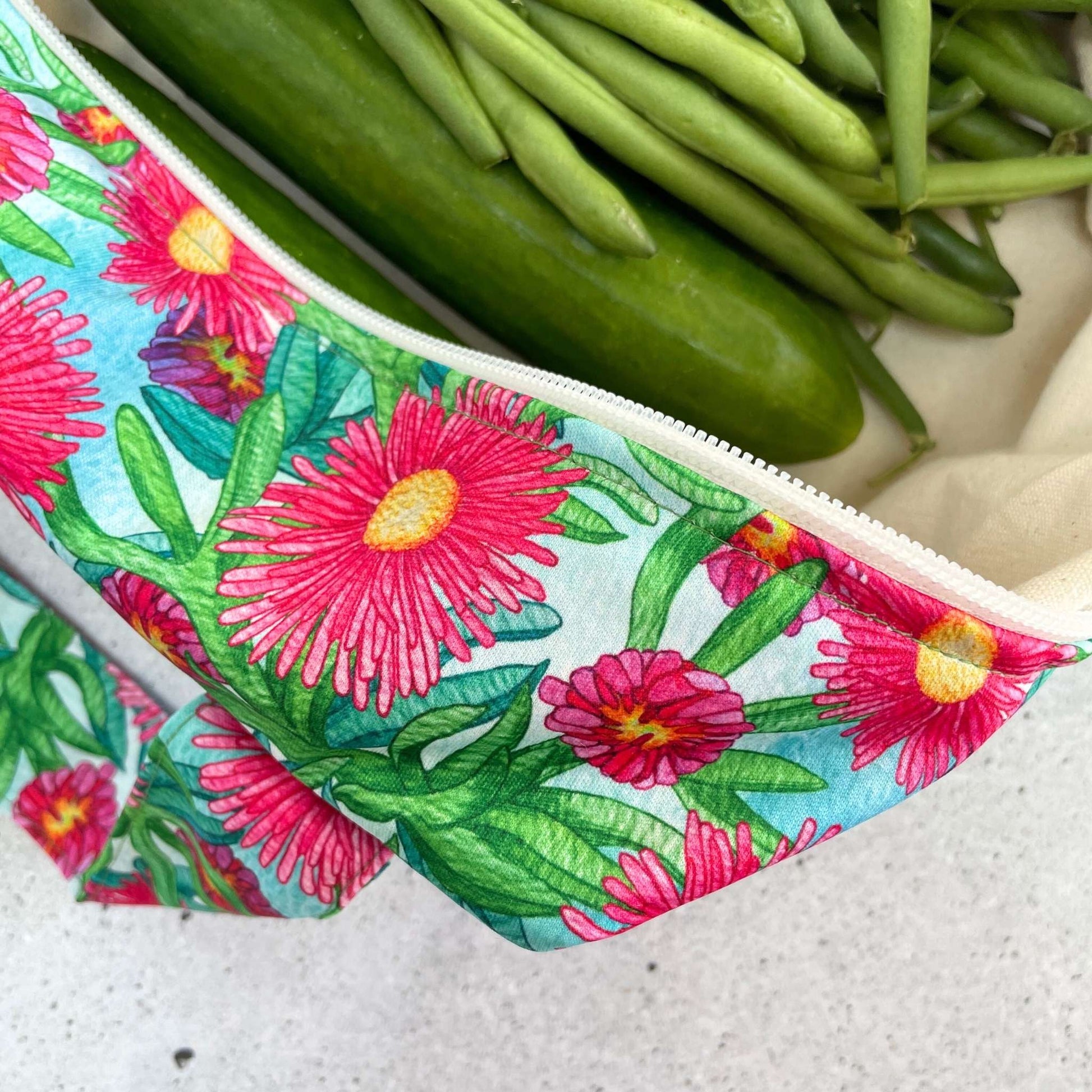 Single Produce Pod reusable veggie storage bag featuring a custom Sea fig print standing open filled with fresh veg and fruit closeup with beans on a stone background.