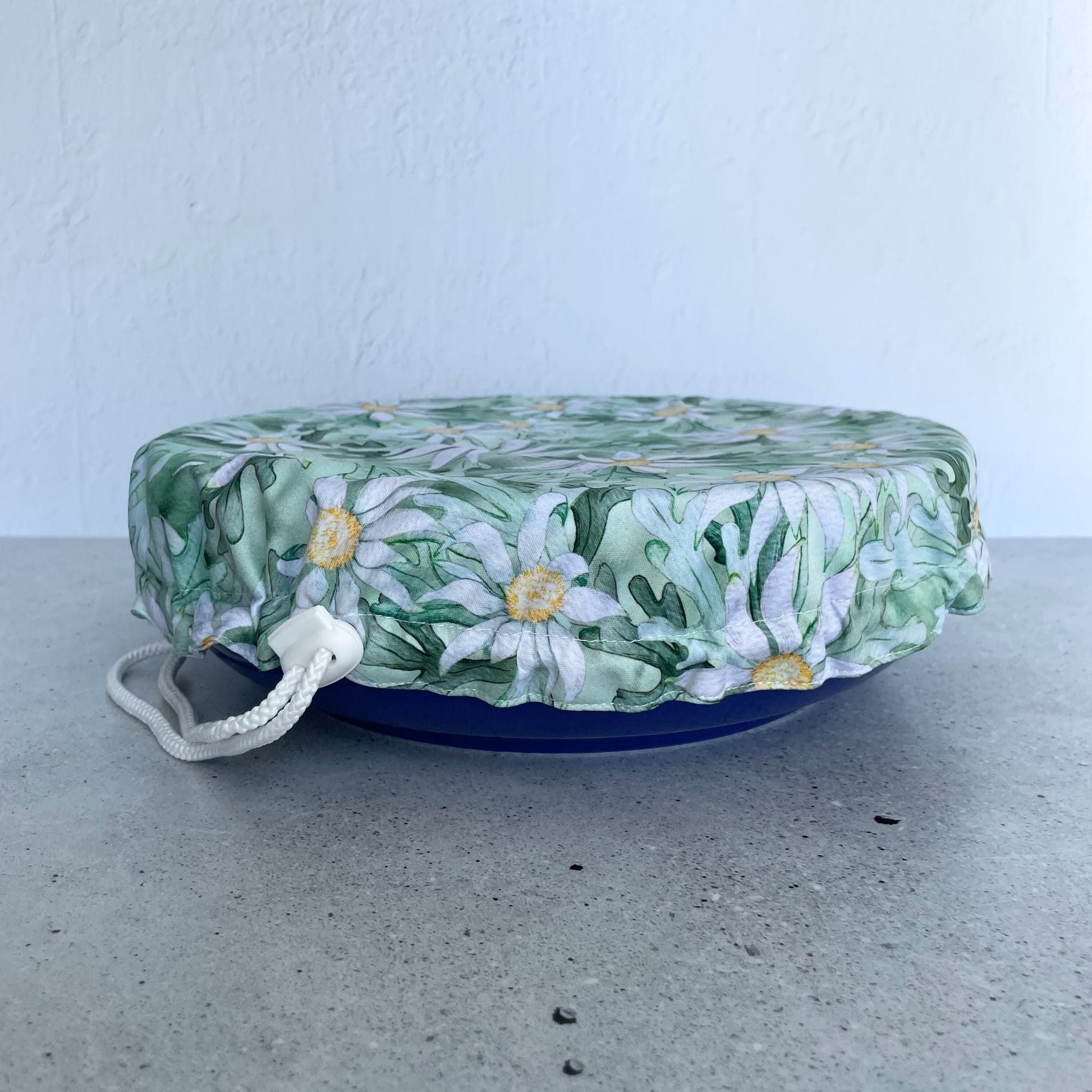 Produce Pod reusable bowl cover in a Flannel Flower print fitted snugly over a white serving dish stone countertop.