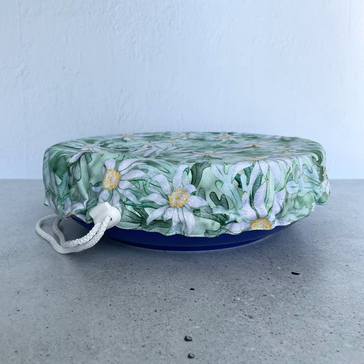 Produce Pod reusable bowl cover in a Flannel Flower print fitted snugly over a white serving dish stone countertop.